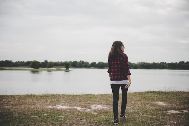 Feliz hipster mujer caminando a través del lago en el fondo de campo de verano.