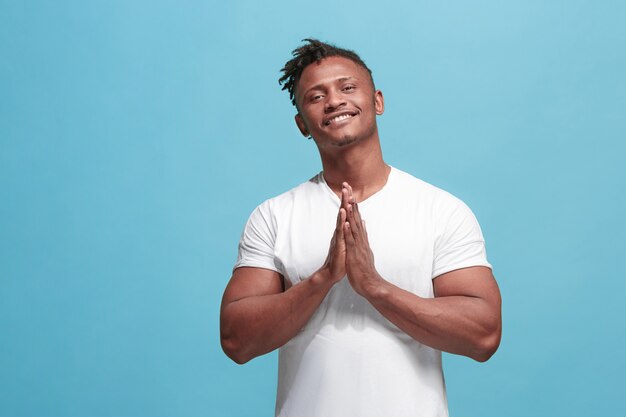 El feliz hombre afroamericano de negocios de pie y sonriendo contra la pared azul