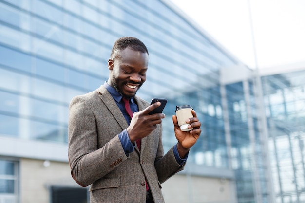 Feliz hombre afroamericano parece suerte leyendo algo en su teléfono inteligente