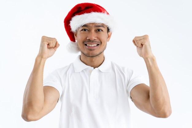 Feliz hombre asiático con sombrero de Santa y puños de bombeo