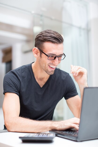 Feliz hombre atractivo trabajando en la computadora portátil en la mesa