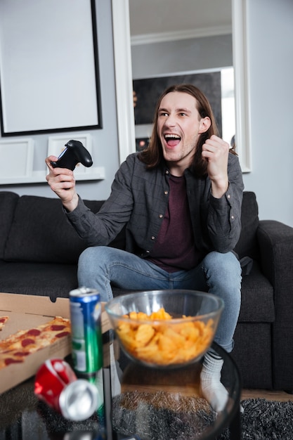 Feliz hombre jugador sentado en casa y jugar juegos