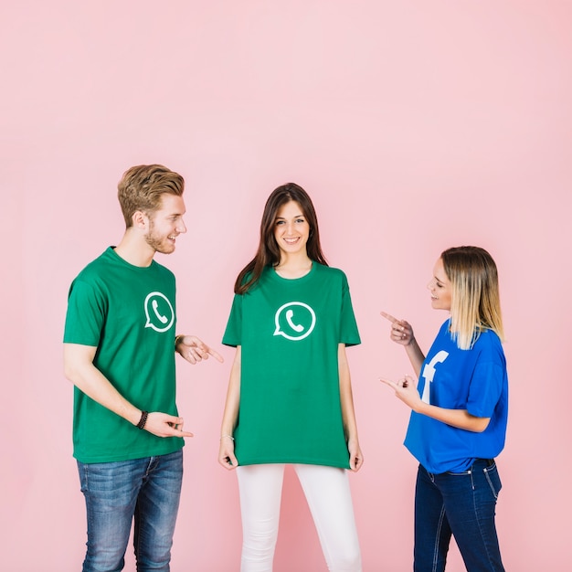 Feliz hombre y mujer apuntando a su amiga con camiseta de whatsapp