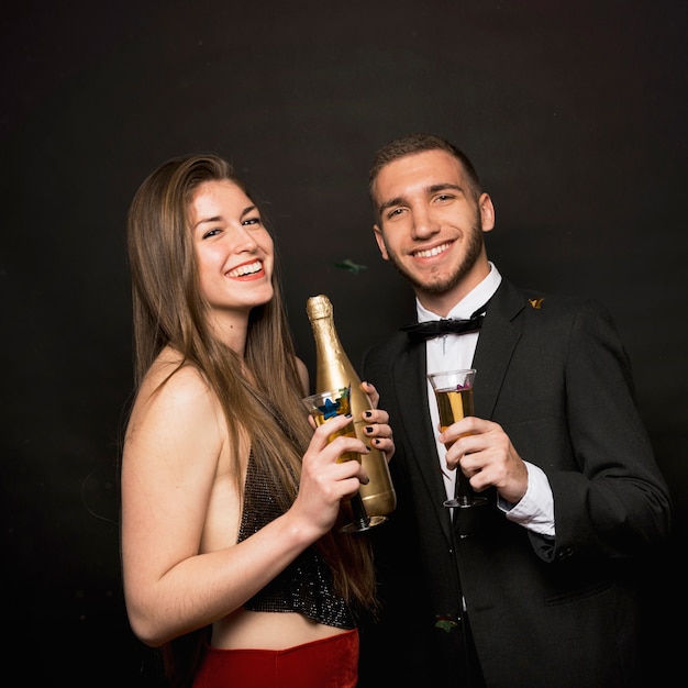 Feliz hombre y mujer con botella y vasos de bebidas