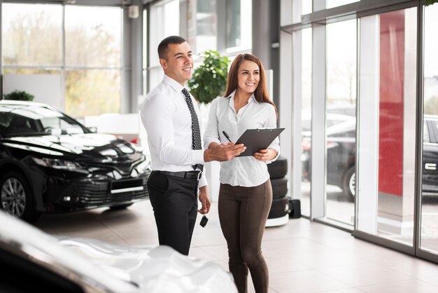 Feliz hombre y mujer cerrar trato de coche