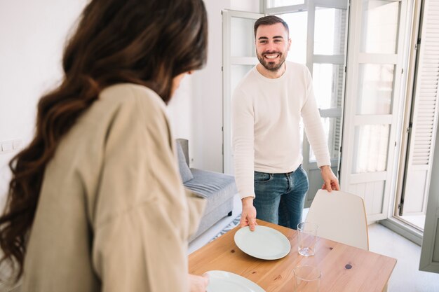 Feliz hombre y mujer sirviendo mesa