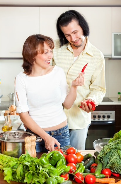 Feliz hombre y mujer con verduras en la cocina