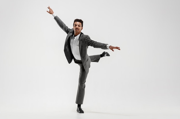 Foto gratuita feliz hombre de negocios bailando en movimiento aislado sobre fondo blanco de estudio. flexibilidad y gracia en los negocios. concepto de emociones humanas. oficina, éxito, profesional, felicidad, conceptos de expresión