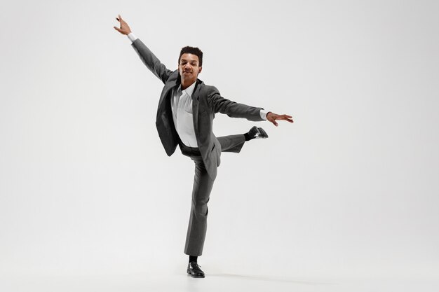 Feliz hombre de negocios bailando en movimiento aislado sobre fondo blanco de estudio. Flexibilidad y gracia en los negocios. Concepto de emociones humanas. Oficina, éxito, profesional, felicidad, conceptos de expresión