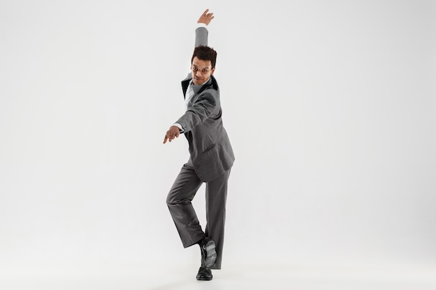 Foto gratuita feliz hombre de negocios bailando en movimiento aislado sobre fondo blanco de estudio. flexibilidad y gracia en los negocios. concepto de emociones humanas. oficina, éxito, profesional, felicidad, conceptos de expresión