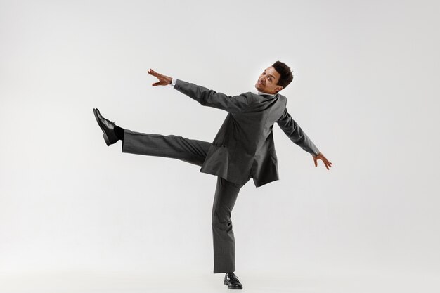 Foto gratuita feliz hombre de negocios bailando en movimiento aislado sobre fondo blanco de estudio. flexibilidad y gracia en los negocios. concepto de emociones humanas. oficina, éxito, profesional, felicidad, conceptos de expresión