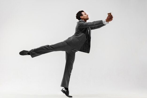 Feliz hombre de negocios bailando en movimiento aislado sobre fondo blanco de estudio. Flexibilidad y gracia en los negocios. Concepto de emociones humanas. Oficina, éxito, profesional, felicidad, conceptos de expresión