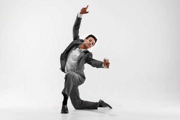 Feliz hombre de negocios bailando en movimiento aislado sobre fondo blanco de estudio. Flexibilidad y gracia en los negocios. Concepto de emociones humanas. Oficina, éxito, profesional, felicidad, conceptos de expresión