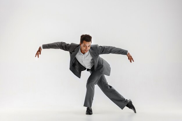 Feliz hombre de negocios bailando en movimiento aislado sobre fondo blanco de estudio. Flexibilidad y gracia en los negocios. Concepto de emociones humanas. Oficina, éxito, profesional, felicidad, conceptos de expresión