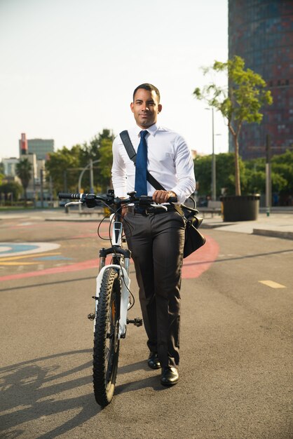 Feliz hombre de negocios caminando con bicicleta en la calle