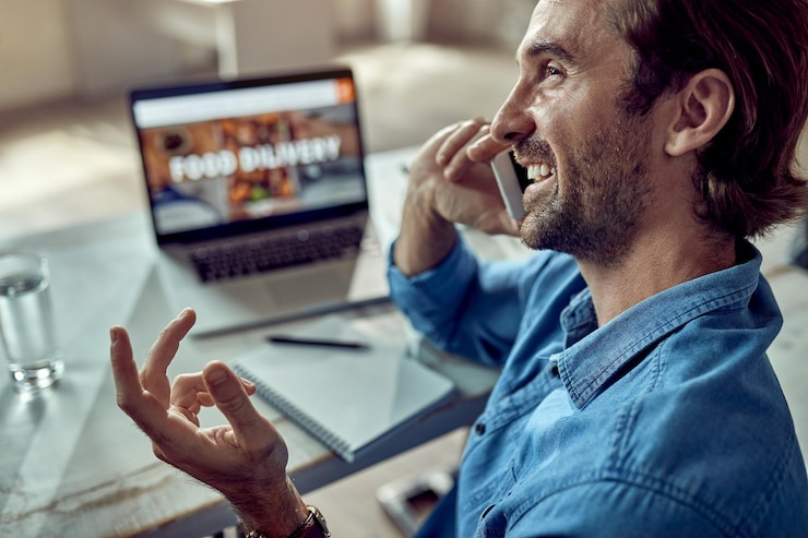 Foto gratuito feliz hombre de negocios comunicándose por teléfono celular mientras trabaja en la oficina