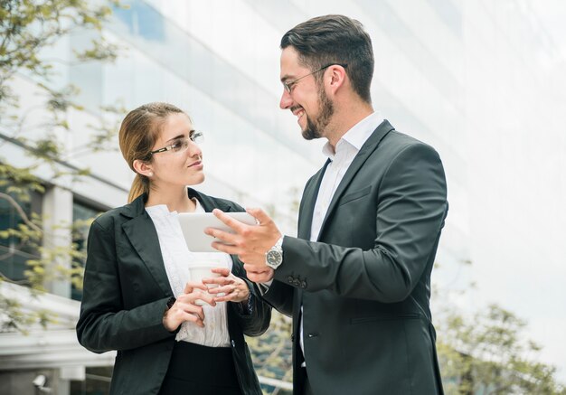 Feliz hombre de negocios y empresaria de pie fuera de la oficina mirando el uno al otro