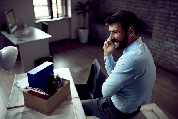 Feliz hombre de negocios está hablando por teléfono móvil durante el primer día de su nuevo trabajo en la oficina