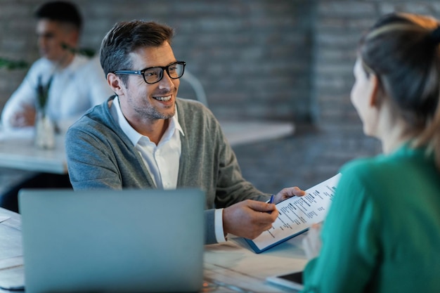 Feliz hombre de negocios hablando con su colega mientras revisa informes financieros en la oficina