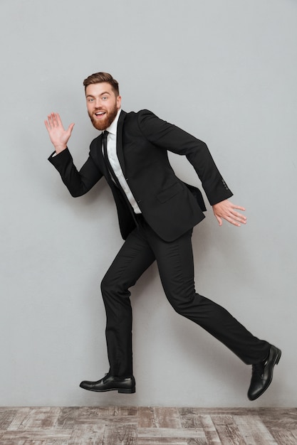 Feliz hombre de negocios sonriente en traje posando mientras salta