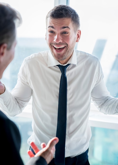 Feliz hombre de negocios teniendo una conversación con su compañero en el lugar de trabajo