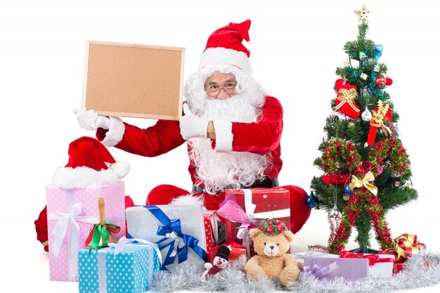 Feliz hombre de Santa Claus con caja de regalo alrededor y sosteniendo la señal para que el texto