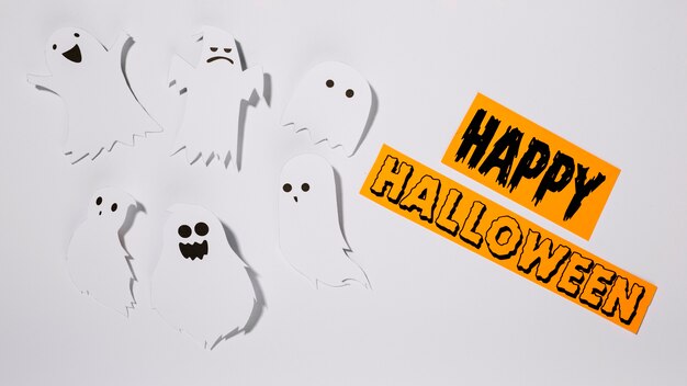 Feliz inscripción de Halloween con fantasmas de papel