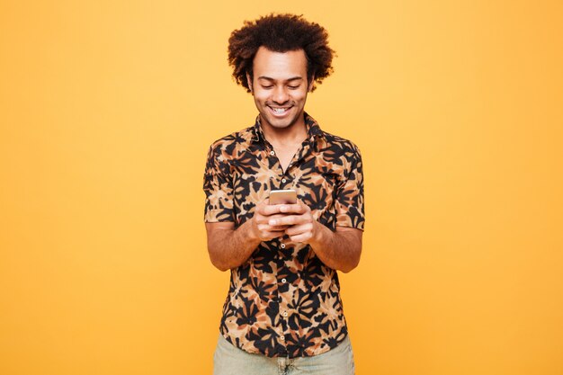 Feliz joven africano chateando por teléfono