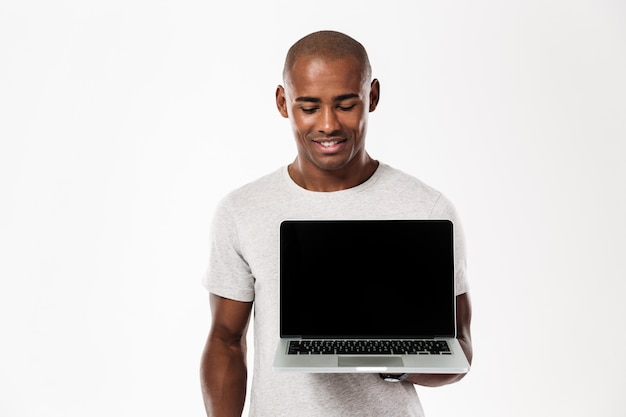 Feliz joven africano mostrando la pantalla del portátil