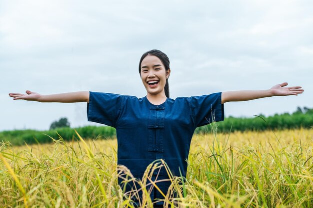 Feliz joven agricultor asiático de pie y con los brazos abiertos en el campo de arroz orgánico