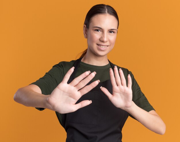 Feliz joven barbero morena en uniforme tiene las manos abiertas