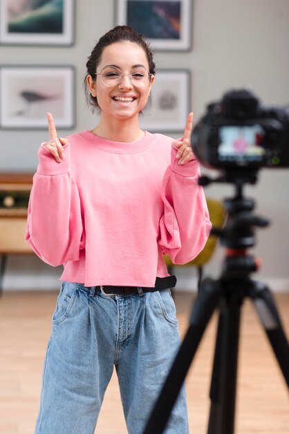 Feliz joven blogger sonriendo a la cámara profesional