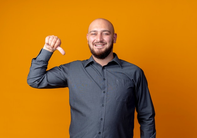 Feliz joven calvo call center hombre apuntando a sí mismo aislado en naranja