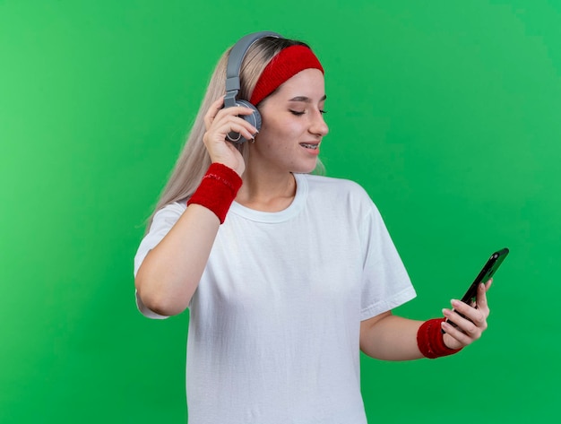 Feliz joven caucásica deportiva con tirantes en los auriculares