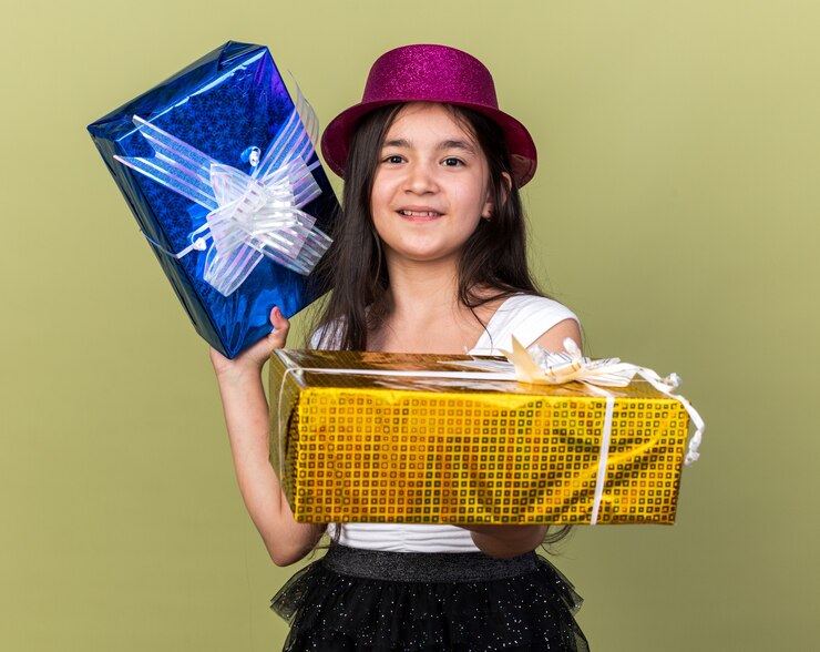 Foto gratuito feliz joven caucásica con gorro de fiesta púrpura sosteniendo cajas de regalo aislado en la pared verde oliva con espacio de copia