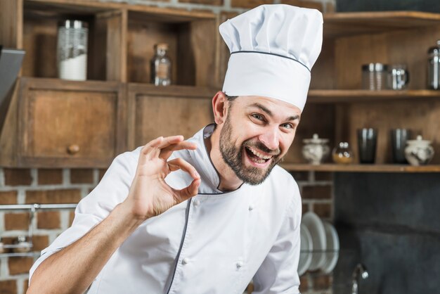 Feliz joven chef hombre haciendo señal de ok