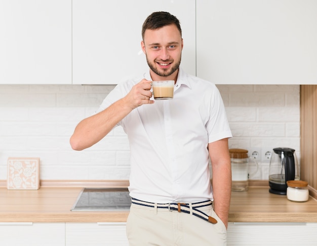 Feliz joven en la cocina con un capuchino