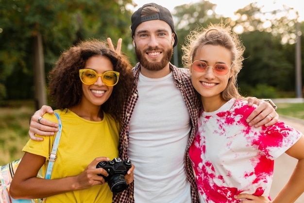 Foto gratuita feliz joven compañía de amigos sonrientes emocionales caminando en el parque con cámara de fotos, hombres y mujeres divirtiéndose juntos