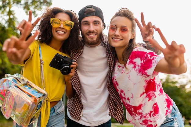 Foto gratuita feliz joven compañía de amigos sonrientes emocionales caminando en el parque con cámara de fotos, hombres y mujeres divirtiéndose juntos