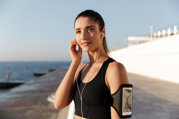 Feliz joven deportes mujer escuchando música al aire libre.