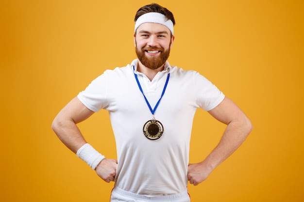 Foto gratuita feliz joven deportista con medalla mirando a cámara.