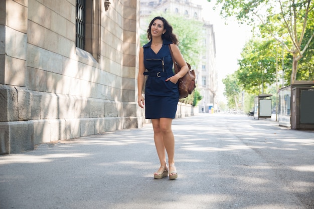 Feliz joven y elegante mujer caminando en la calle de la ciudad