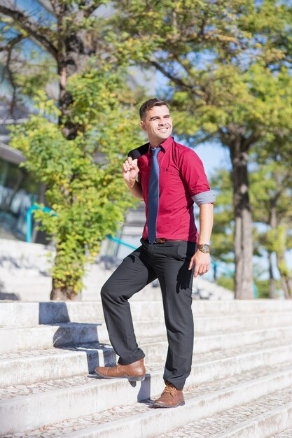 Feliz joven empresario va arriba al aire libre