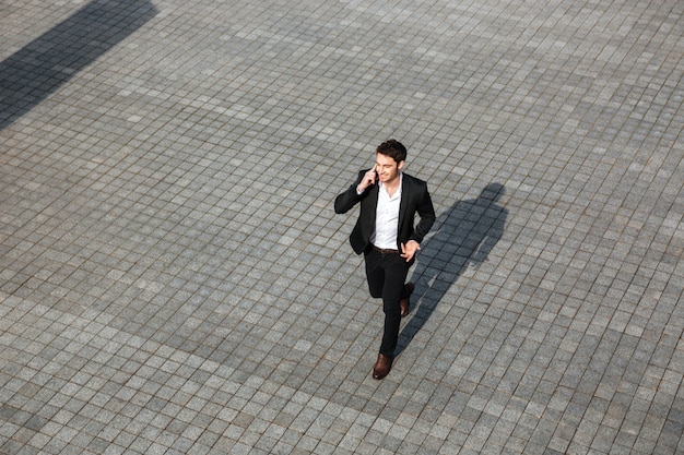 Foto gratuita feliz joven empresario caminando al aire libre