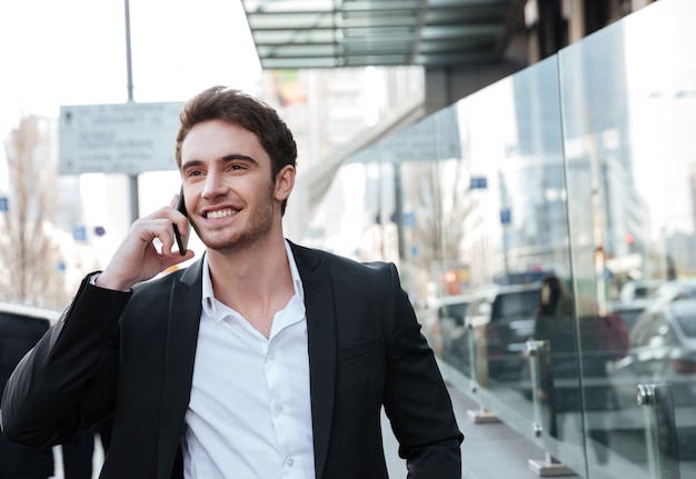 Feliz joven empresario caminando cerca del centro de negocios.