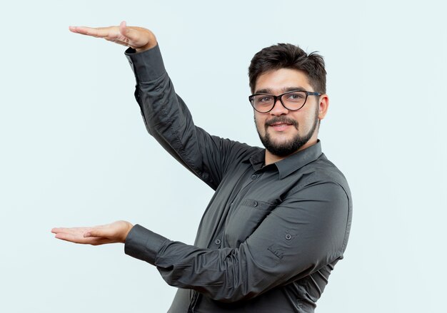 Feliz joven empresario con gafas mostrando tamaño aislado sobre fondo blanco.