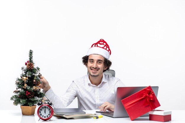 Feliz joven empresario con sombrero de santa claus divertido decorar el árbol de Navidad y celebrar la Navidad en la oficina sobre fondo blanco.