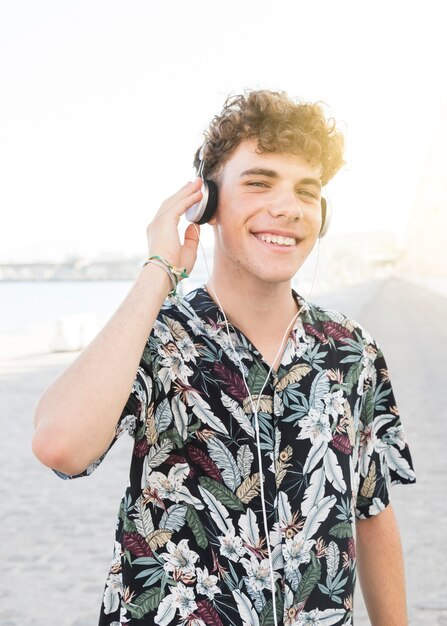 Feliz joven escuchando música en auriculares al aire libre