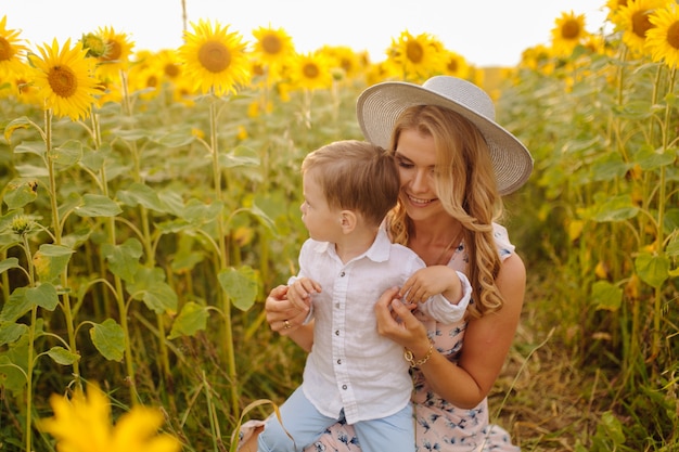 Feliz joven familia, madre, padre e hijo, sonríe, abraza y abraza en el campo de girasol