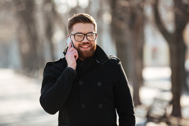 Feliz joven hablando por teléfono celular al aire libre en invierno